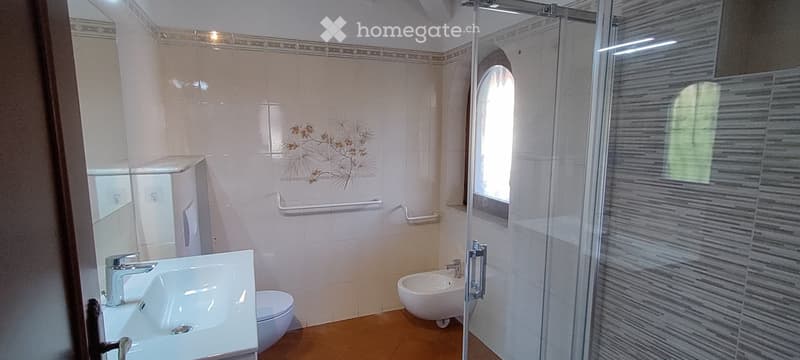 tiled bathroom with toilet, bidet, sink, shower, window