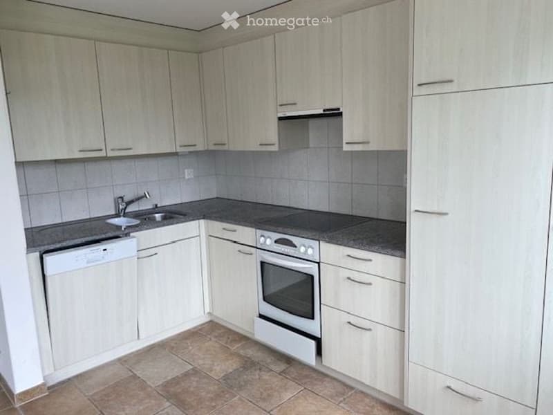 Modern kitchen with white cabinets, tiled backsplash, granite countertop, sink, faucet, oven, and dishwasher.