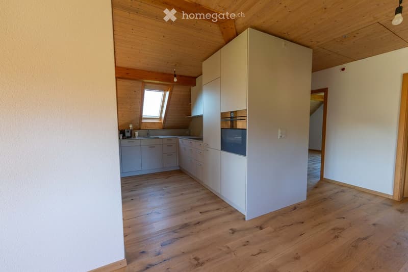 Modern kitchen with light-colored cabinets, wooden flooring, and a window above the sink.