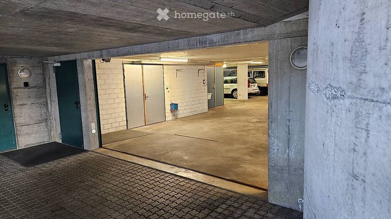 concrete walls, tile flooring, two parking spaces, white and green doors, overhead lighting