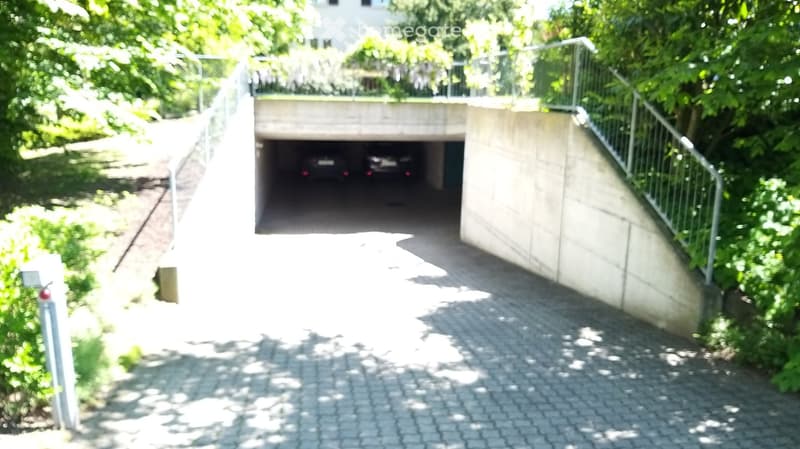 Underground garage entrance, paved ground, car parked inside