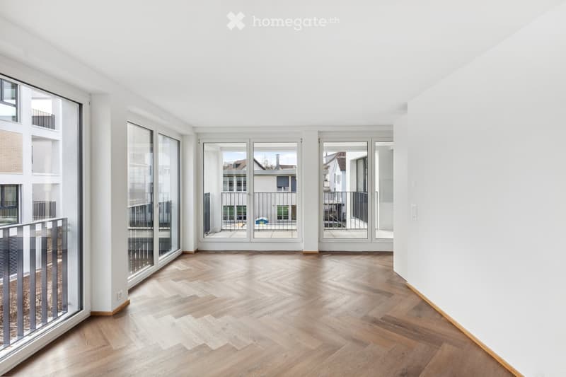 Empty room with wooden herringbone flooring, large glass doors leading to a balcony, white walls, and modern lighting fixtures.
