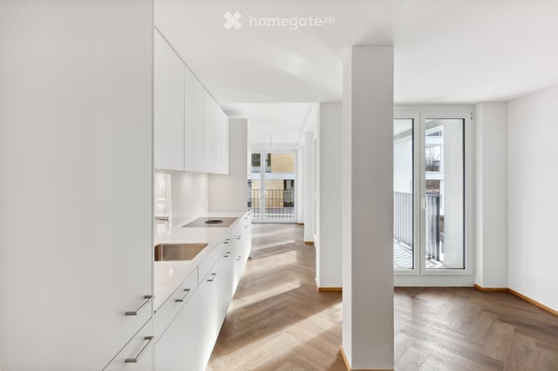 Modern kitchen with white cabinets, stainless steel sink, and stove, featuring a herringbone wooden floor and large windows.
