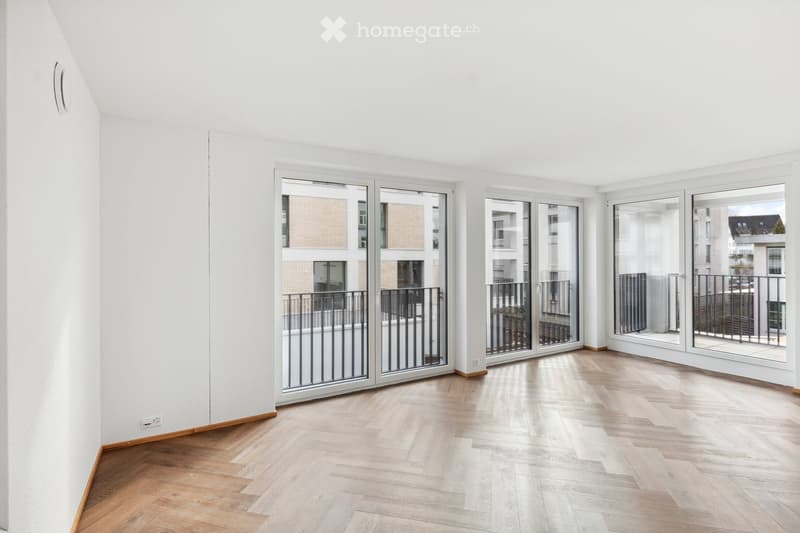 Bright, empty room with wooden flooring and large sliding glass doors leading to a balcony.