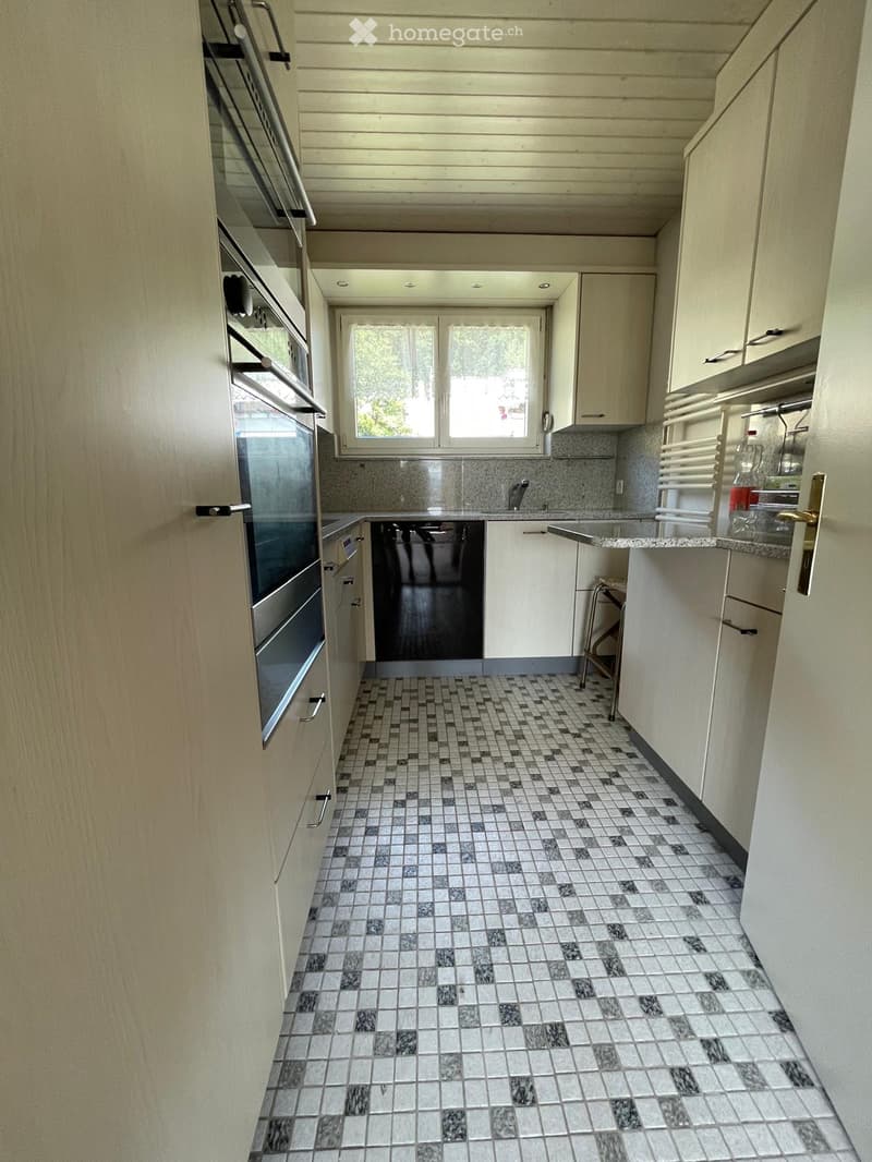 Modern kitchen with white cabinets, stainless steel appliances, and a checkered tile floor.