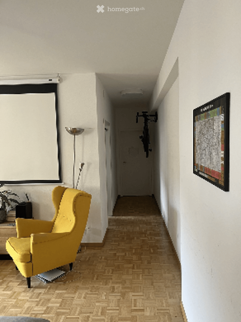 A modern hallway with a yellow armchair, floor lamp, screen, plant, and picture frame on the wall.