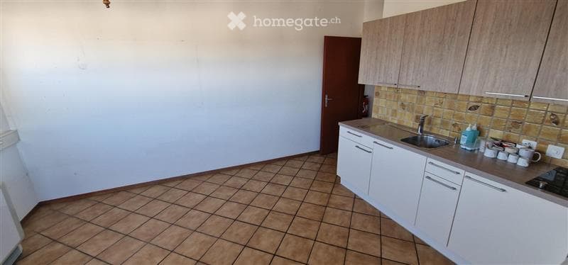 Modern kitchen with white cabinets, tiled backsplash, and a tiled floor. Features a sink, faucet, stove, and several cups on the counter.