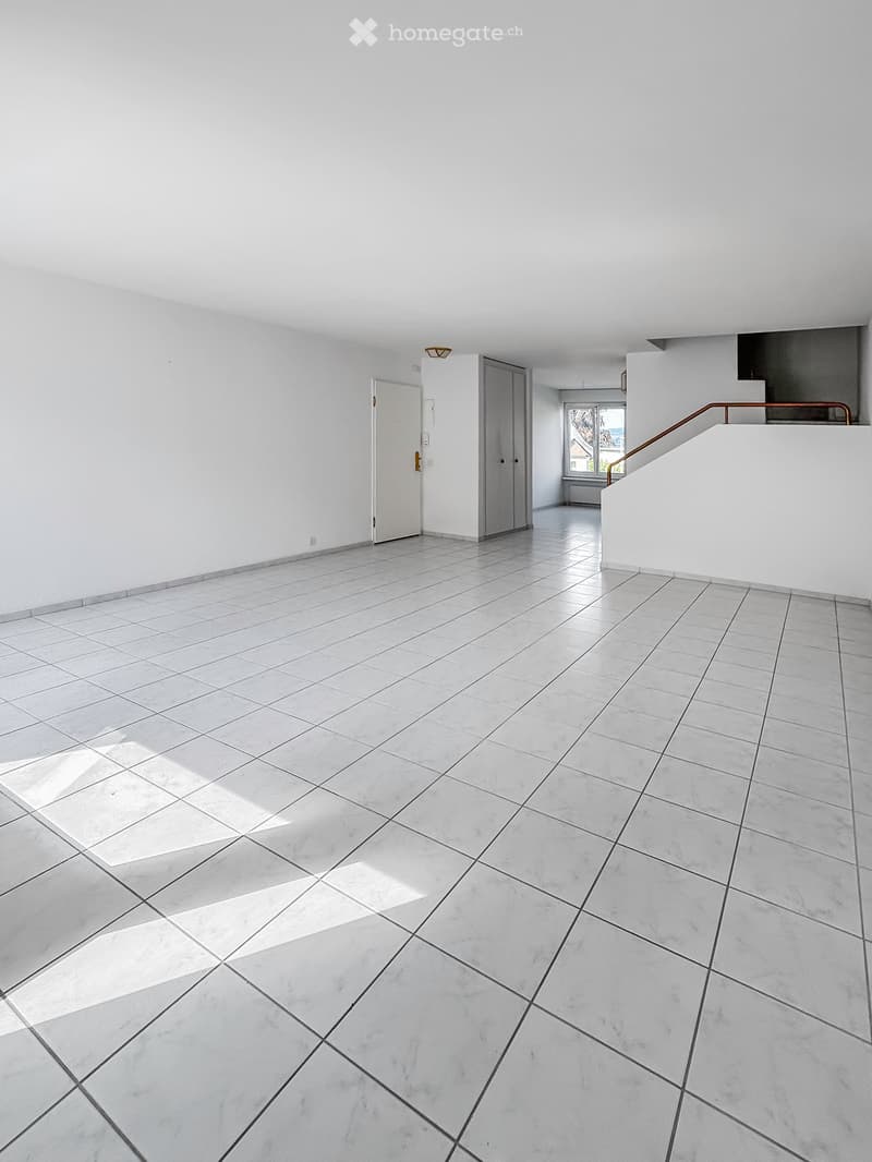 Empty room with white walls, tiled floor, and a staircase leading to another level. No furniture or equipment is present.