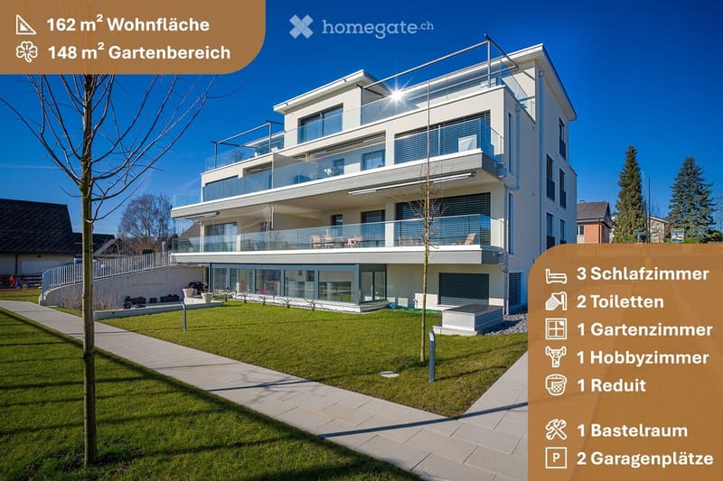 Modern two-story house with large glass balconies, raised ground floor, garage, and well-maintained garden area.