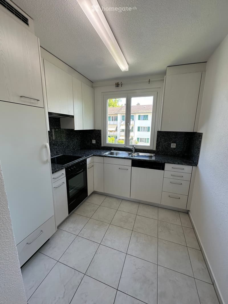 Modern kitchen with white cabinets, granite countertops, and stainless steel appliances including a refrigerator, oven, sink, and dishwasher.