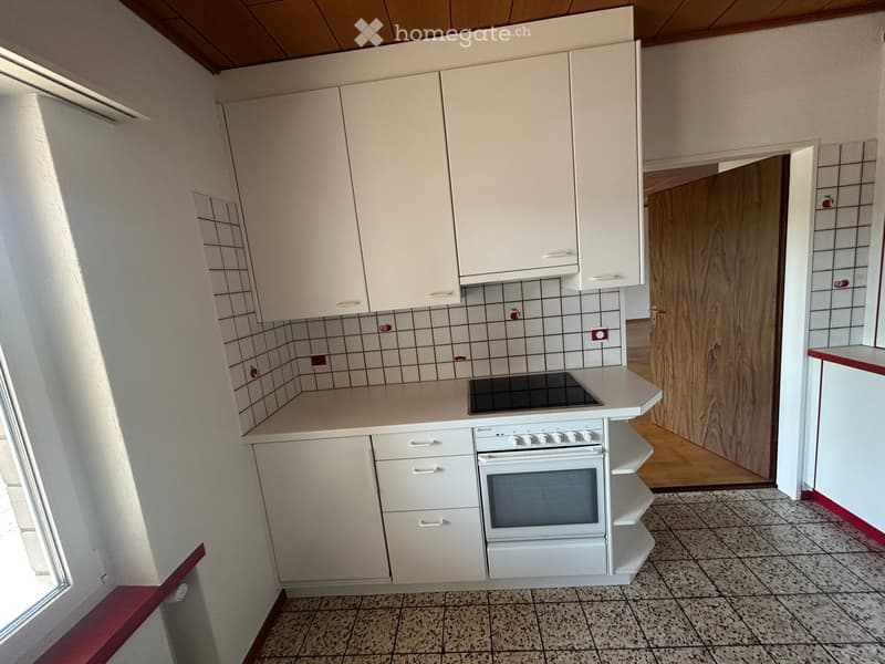 Modern kitchen with white cabinets, a built-in oven, and a stove, featuring tiled walls and a tiled floor.
