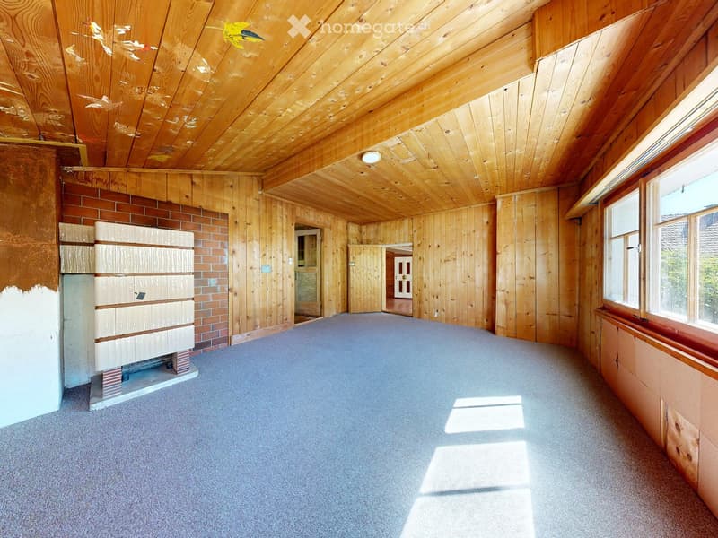 Empty room with wooden walls and ceiling, carpeted floor, fireplace, and large windows allowing natural light.