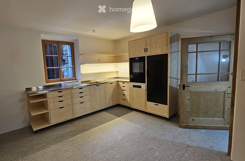 empty kitchen with wooden cabinets, wooden floor, window with glass panes, metal island with drawer, dishwasher