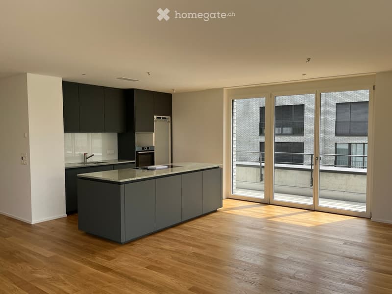 Modern kitchen with dark grey cabinets, a central island, and large glass doors leading to a balcony.