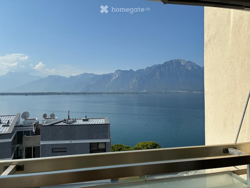 Balcony overlooking a large lake with distant mountains in the background.
