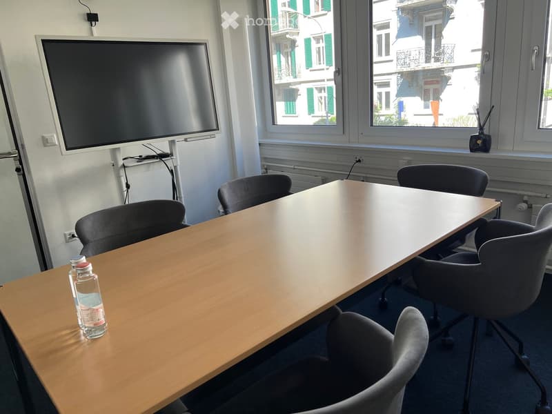 conference room with a large table, chairs, a flat screen TV, and windows