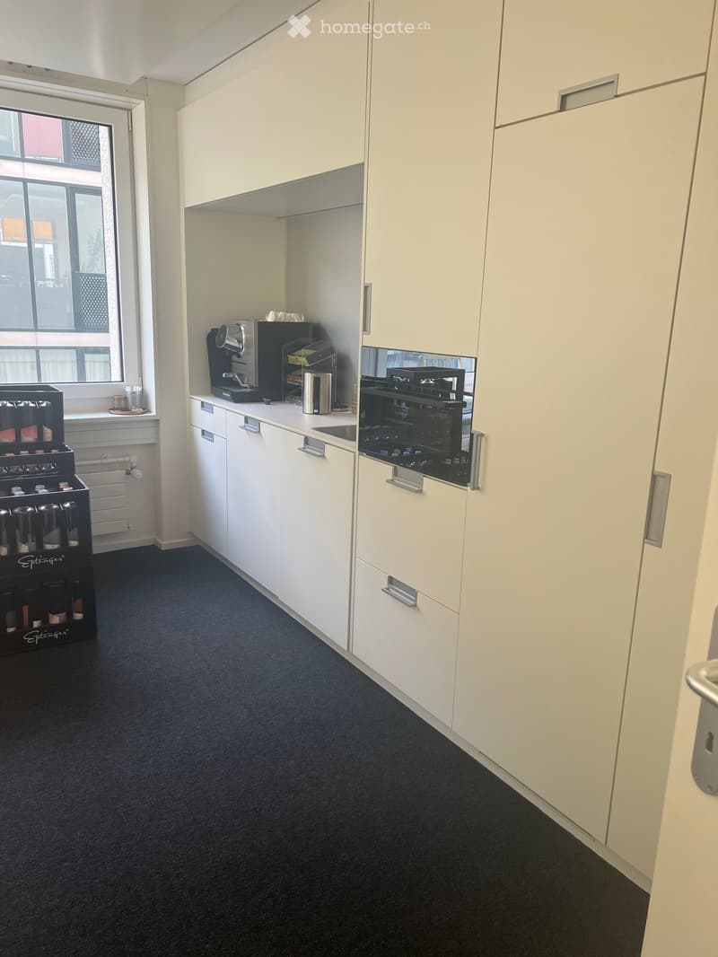 modern kitchen with white cabinetry, black flooring, a coffee maker on the counter, a refrigerator in the left corner, and an oven on the right side