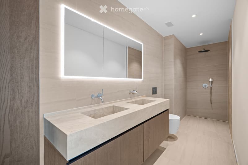 Modern bathroom with double sink, large mirror with LED lighting, sleek wooden cabinetry, and a separate shower area.