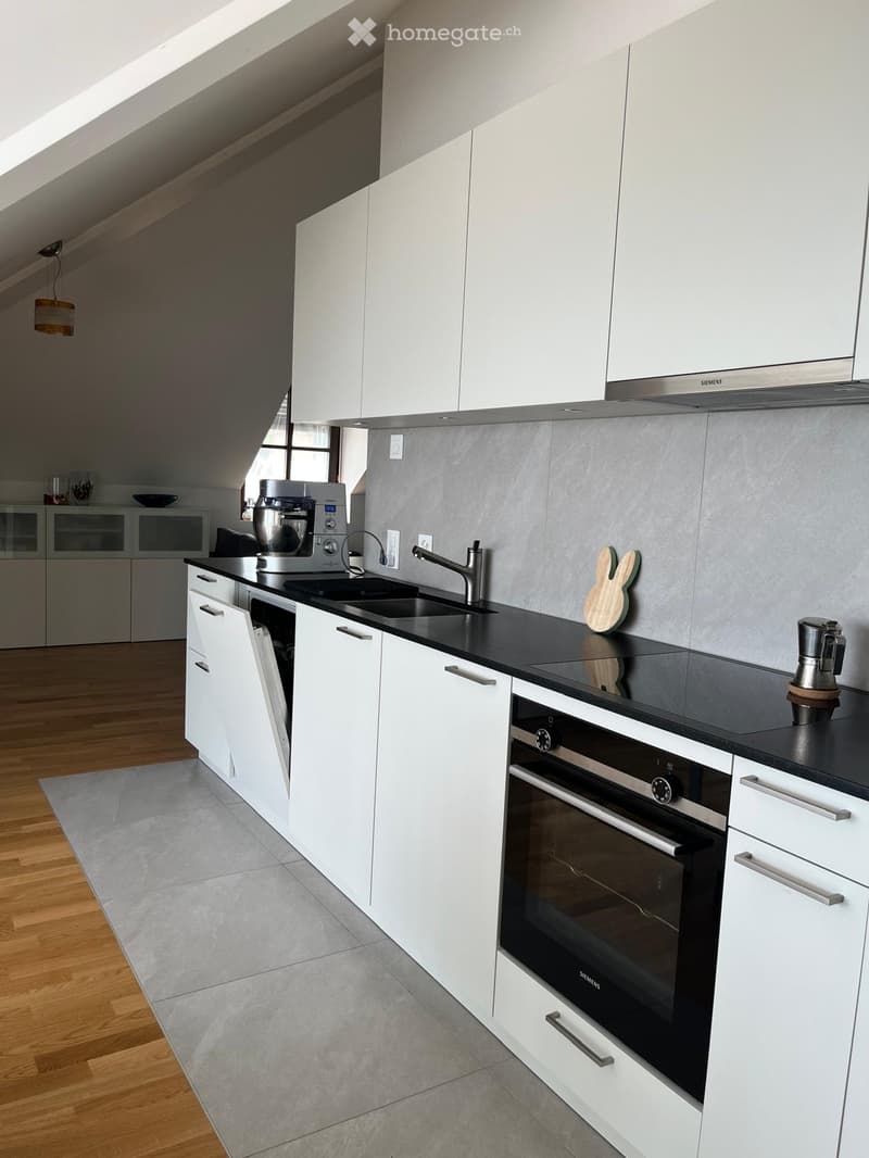 Modern kitchen with white cabinets, black countertops, stainless steel appliances, and a sleek design. Features include a sink, faucet, oven, coffee maker, and a kitchen island.