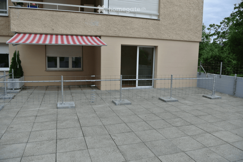 Balcony with tiled floor, metal fence, and awning attached to a building.