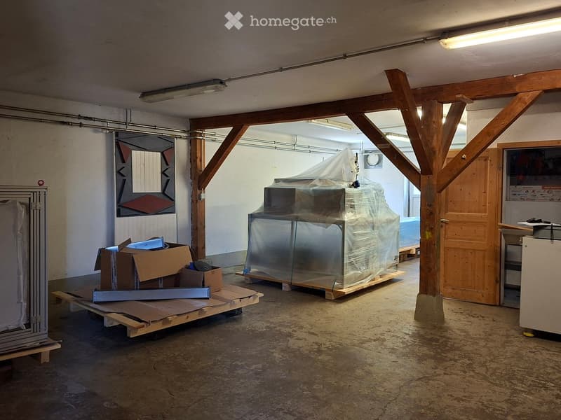 Empty room with exposed wooden beams, concrete floor, and covered furniture. No furniture or equipment visible.