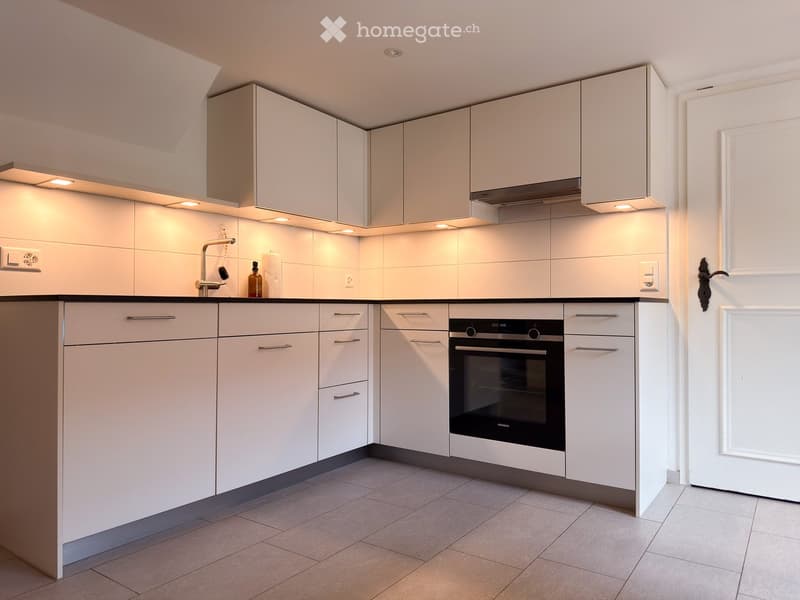 Modern kitchen with white cabinets, stainless steel oven, and sleek design.