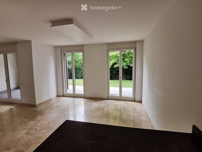 Empty room with tiled floor, white walls, large sliding glass doors leading to a patio, and a ceiling light fixture.