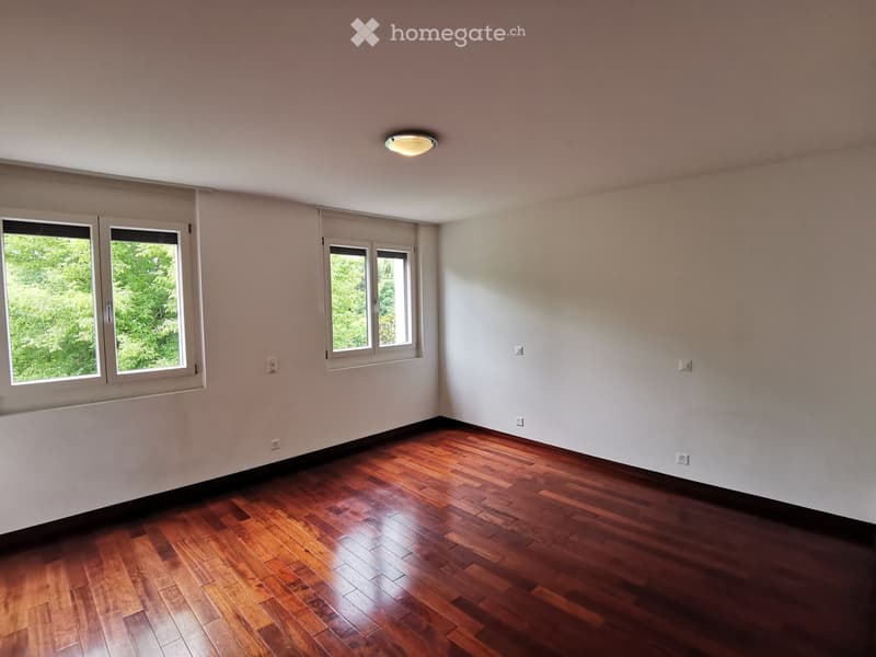 Empty room with wooden flooring, white walls, and multiple windows allowing natural light. No furniture or equipment is present.
