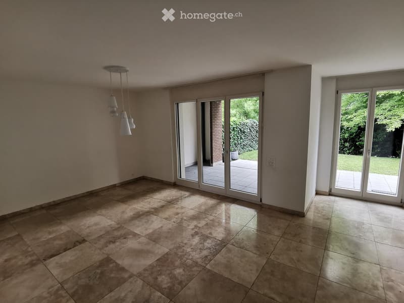 Empty room with tiled flooring, large sliding glass doors leading to an outdoor area, and a hanging light fixture.