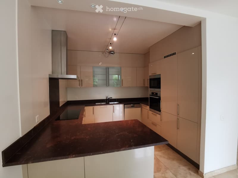Modern kitchen with light-colored cabinets, stainless steel appliances, and a dark countertop.