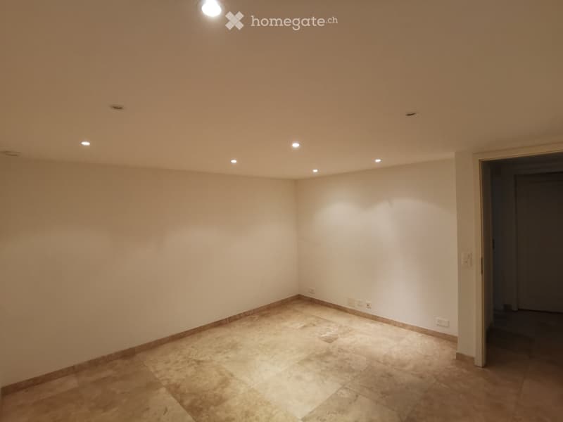 Empty room with beige tiled floor, white walls, and recessed lighting. No furniture or equipment present.