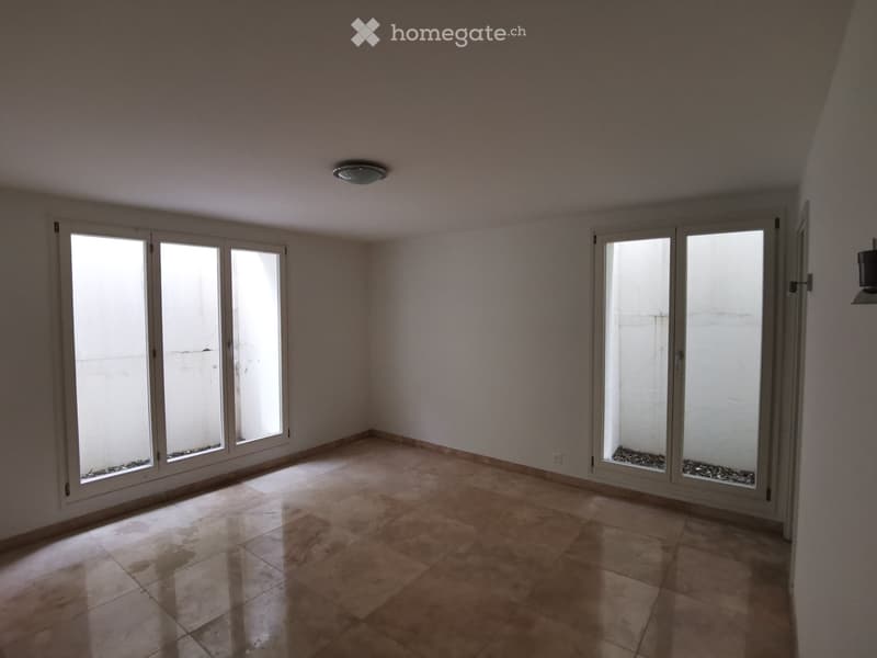 Empty room with tiled floor, large sliding glass doors, and white walls.