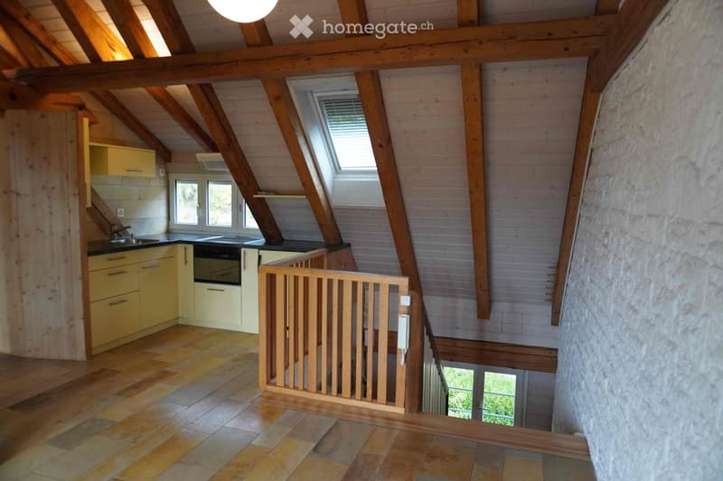 Bright, open kitchen with wooden beams, tiled floor, and yellow cabinets. Features a sink, faucet, and oven, with a wooden staircase leading to an upper level.