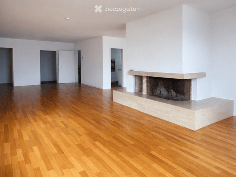 Empty room with wooden flooring and a fireplace against one wall. No furniture or furnishings are present.