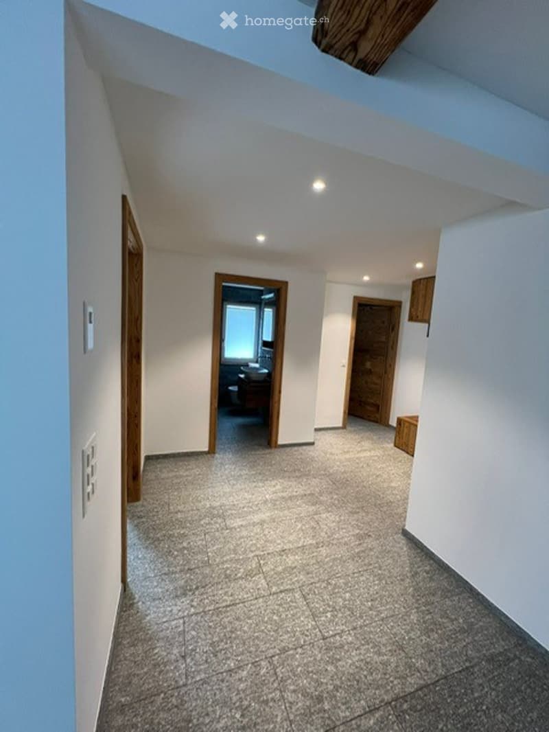 Empty hallway with tiled floor, white walls, and several doors leading to other rooms.