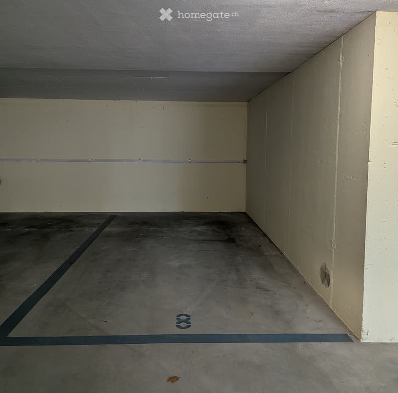 Empty concrete garage space with bare walls and a numbered designation '8' on the floor.