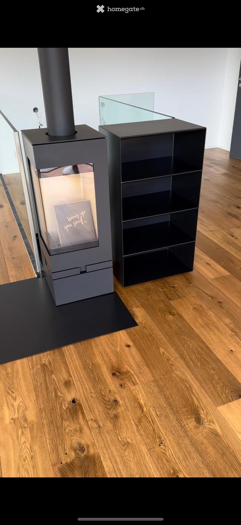 Modern living room with a sleek black fireplace and a matching black shelf unit, featuring a wooden floor.