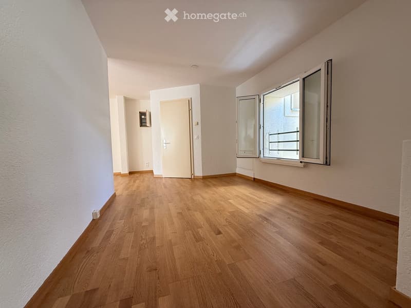 Empty room with wooden flooring, white walls, and large windows with blinds. No furniture or equipment present.