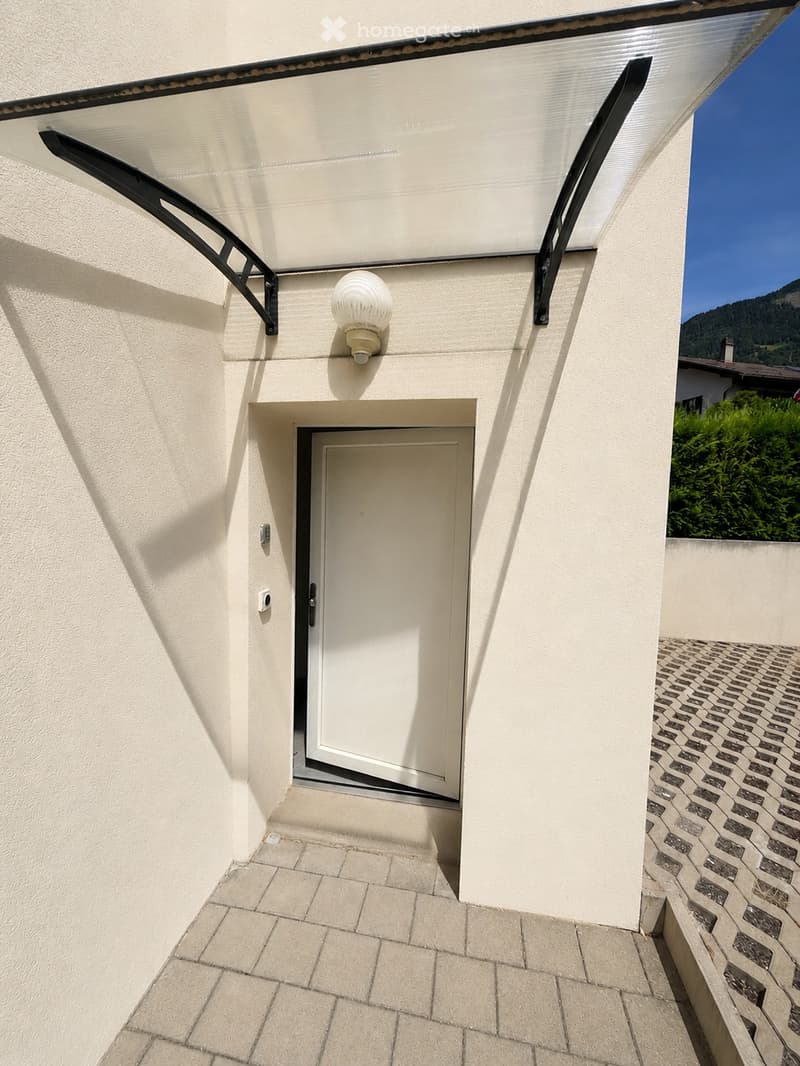 Balcony with a white door, modern awning, and a round wall-mounted light fixture.