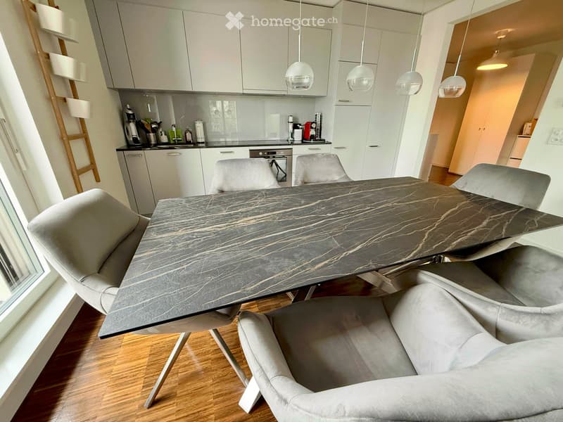 Modern kitchen and dining area with a marble dining table, four chairs, white cabinets, and various kitchen appliances.