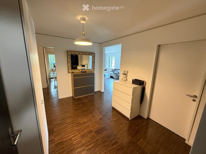 Hallway with wooden flooring, a white dresser, a mirror, and a small toy on top of the dresser.