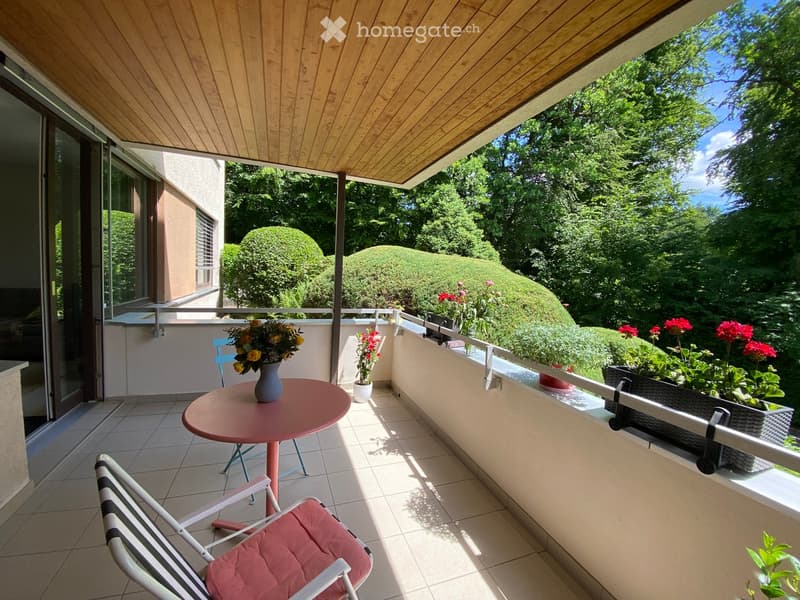 Balcony with a wooden ceiling, tiled floor, and outdoor furniture including a round table, chair, and flower pots.