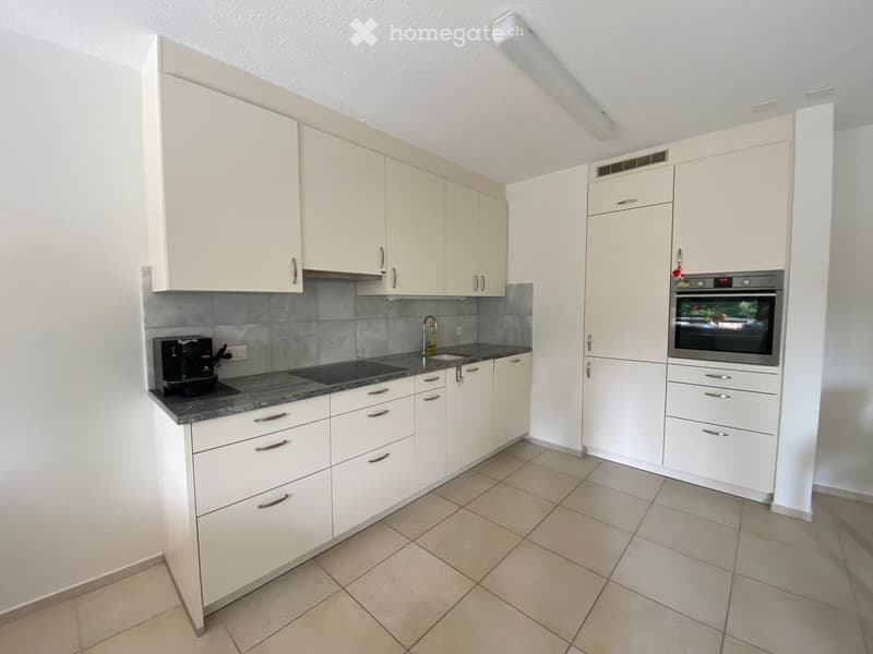 Modern kitchen with white cabinets, granite countertop, coffee maker, sink, and built-in oven.