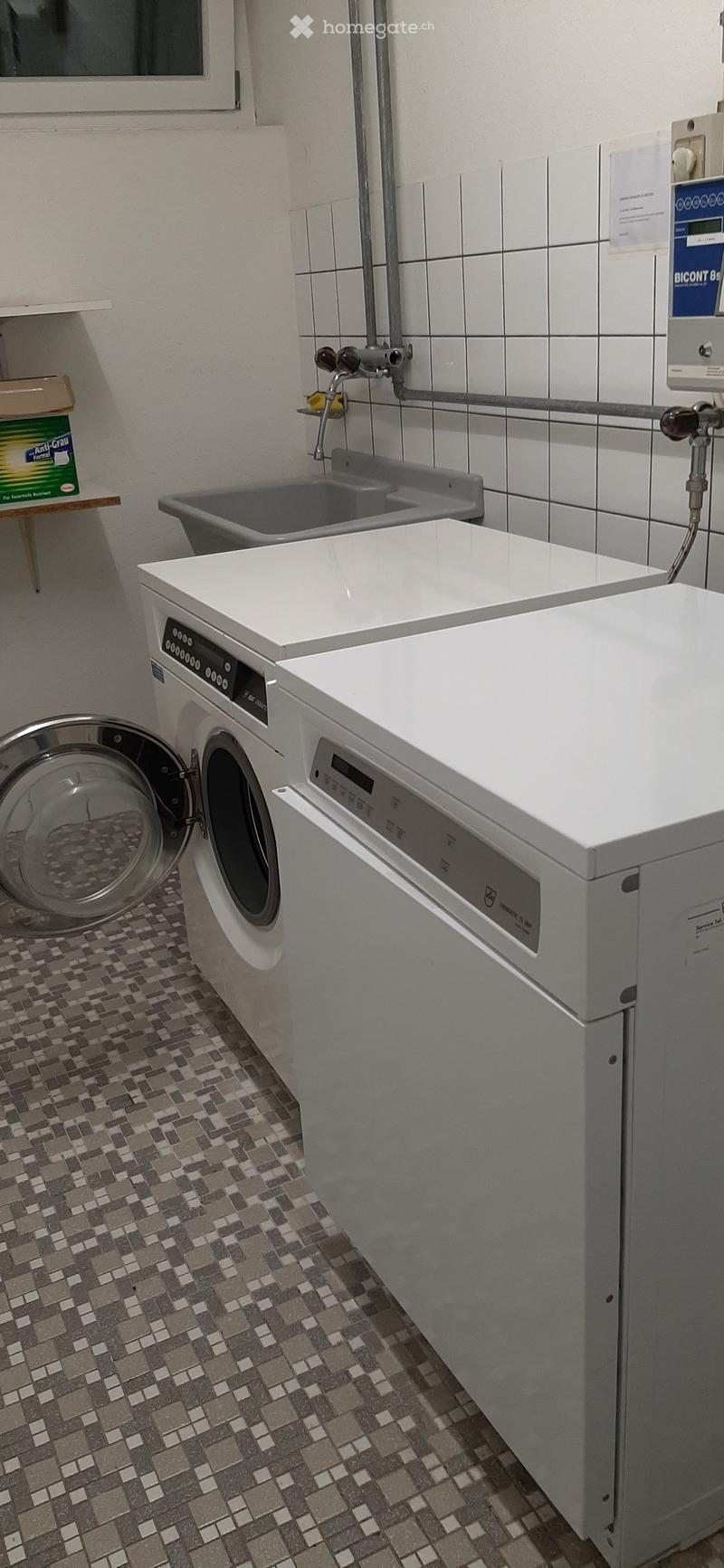 Bathroom with a washing machine, dishwasher, and sink, featuring tiled walls and a mosaic tile floor.