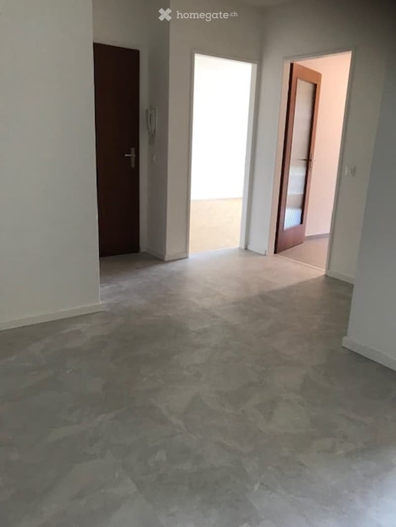 Empty room with grey tiled floor, white walls, and two doors leading to other spaces.