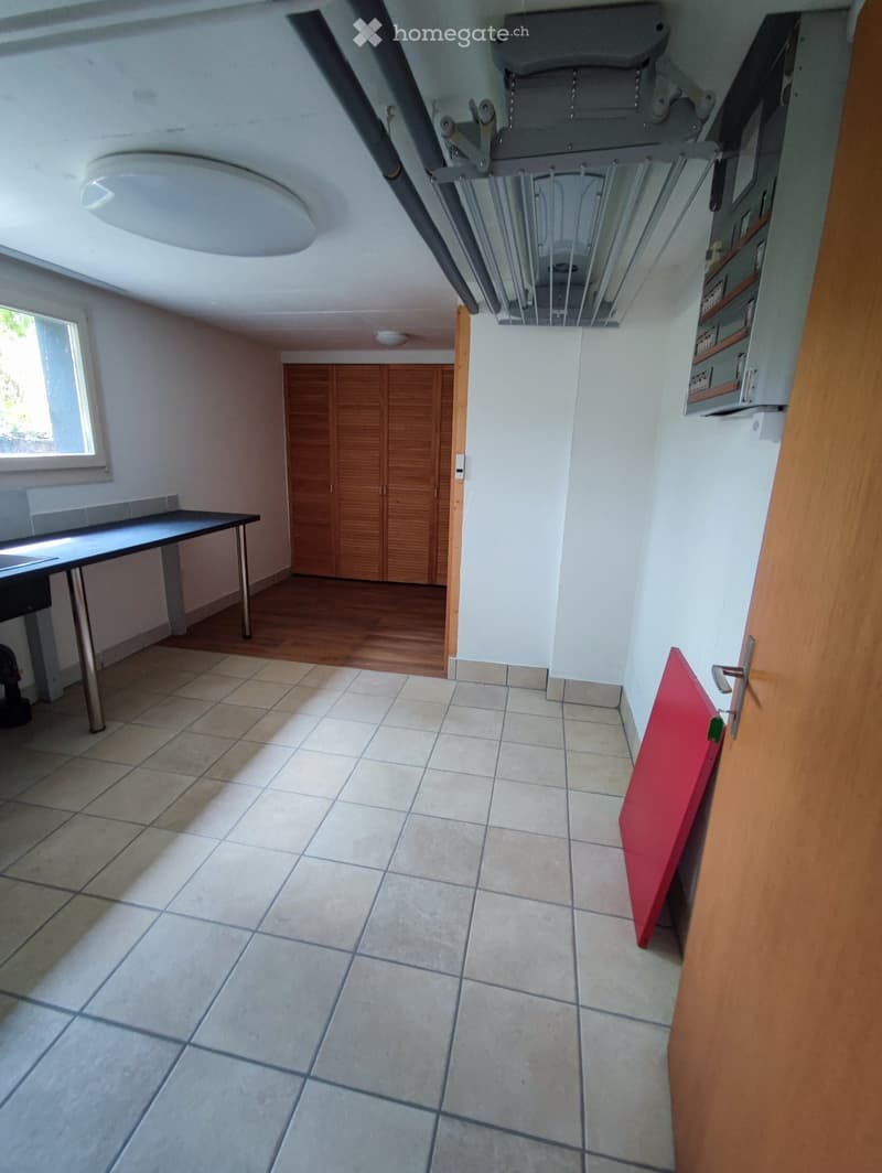 Empty room with tiled floor, wooden cabinet, and a small table near the window. No furniture or personal items present.