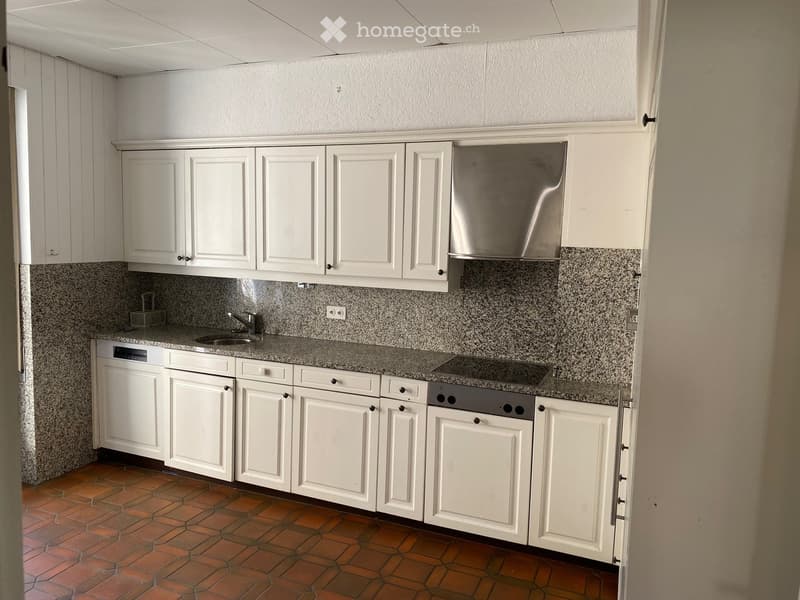 Modern kitchen with white cabinets, granite countertop, stainless steel appliances, and tiled floor.