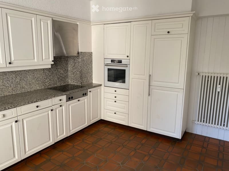 Modern kitchen with white cabinets, granite countertops, stainless steel appliances, and terracotta tiled floor.