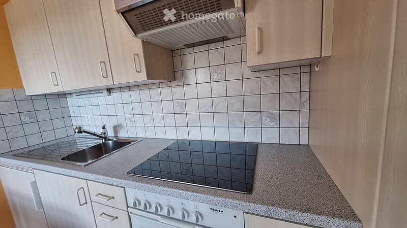 Modern kitchen with white cabinets, granite countertops, stainless steel sink, induction cooktop, and built-in oven.