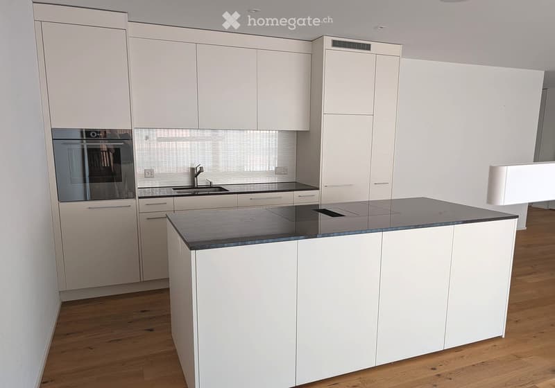 Modern kitchen with white cabinets, a central island, and a black countertop. Features include an oven, sink, and faucet.